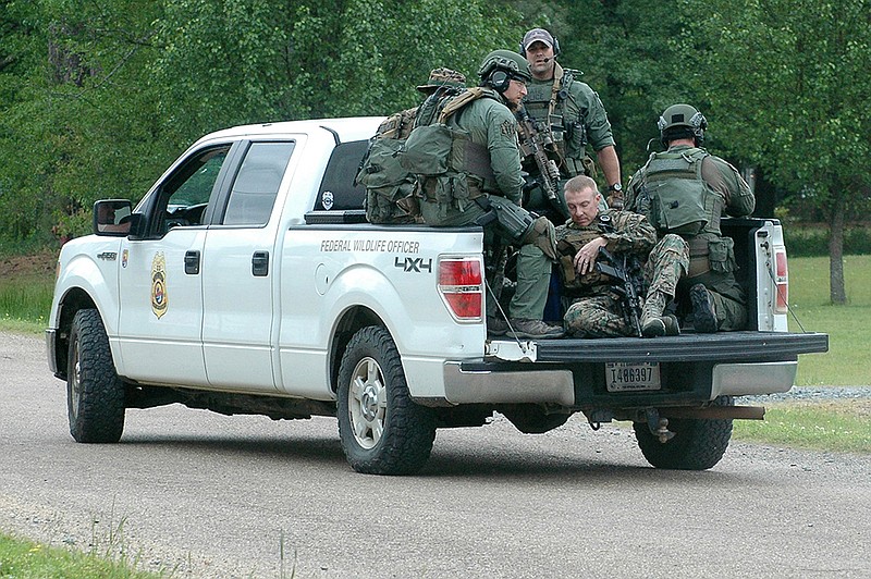 An Arkansas State Police SWAT team hangs onto the back of a pickup Friday, Apr. 15, 2016 en route to a house in Foreman, Ark., where a man was threatening officers and said he wouldn't come out of the house alive. The man was stunned by an officer with a Taser and then arrested without anyone being hurt, Little River County Sheriff Gary Gregory said.