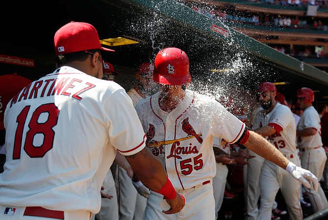St. Louis Cardinals' Stephen Piscotty, right, is splashed with water by teammate Carlos Martinez after hitting a three-run home run during the second inning of a baseball game against the Cincinnati Reds Saturday, April 16, 2016, in St. Louis.
