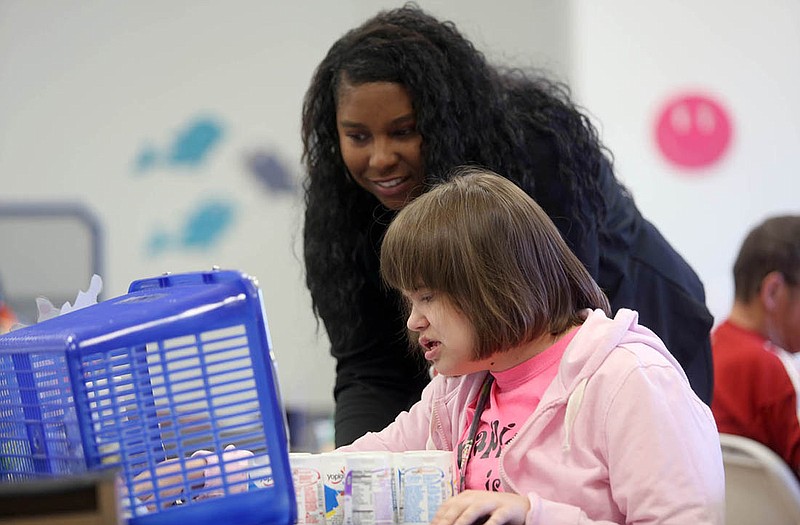 Student Kristin McCuskey, bottom, works with employee Andreon Mitchell, back, at Day Solutions adult learning center for those with learning disabilities. The learning center marked its one-year anniversary on April 1.