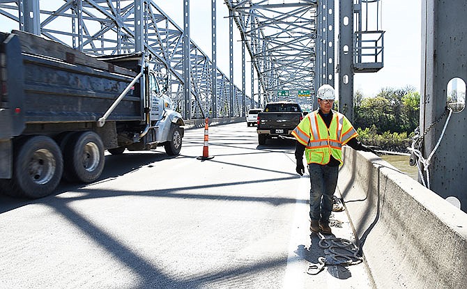Traffic passes by as worker Javier Torres looks over the side of the westbound U.S. 50/63 Missouri River bridge Thursday in Jefferson City.
