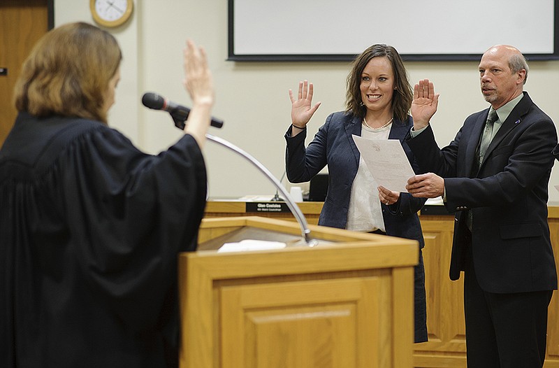 Newly elected Ward 3 City Council member Erin Wiseman, center, rais- es her right hand alongside Ward 2 council member Rick Mihalevich as Circuit Judge Patricia Joyce administers the oath of office for newly elected and reelected members of the Jefferson City Council during Mondayâ€™s meeting.
