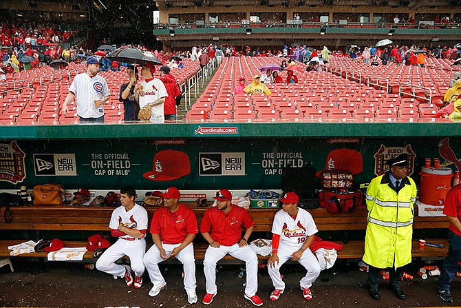 Members of the St. Louis Cardinals, from left to right, Aledmys Diaz, Brayan Pena, Jhonny Peralta and Ruben Tejada sit in the dugout during a rain delay in the seventh inning of a baseball game against the Chicago Cubs Wednesday, April 20, 2016, in St. Louis. 