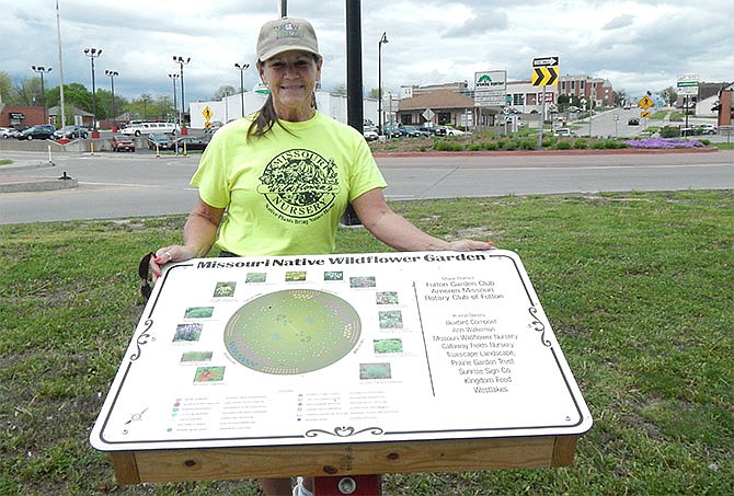 Diane Neterer, president of the 80-year-old Fulton Garden Club, stands by a schematic showing the native plantings in the traffic circle on Business 54 in Fulton. Club members planted the circle a year ago.
