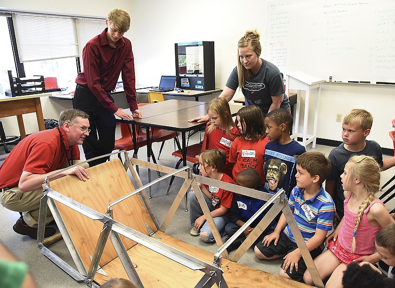 Students in Jaci Jacksonâ€™s first-grade class at Moreau Heights learned the importance of math in engineering Friday during a lesson in a Project Lead The Way class at Nichols Career Center. They watch as David Straatmann puts down the bridge flooring on the truss bridge design that the senior project engineer for Bartlett & West Inc. can take with him for demonstration purposes. Standing next to Straatmann is sophomore Nathan Erickson and behind students is Jackson.