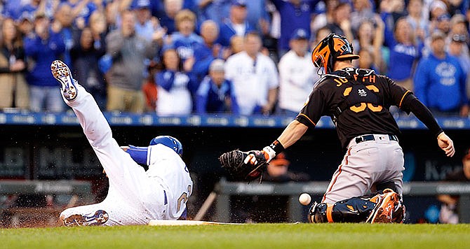 Kansas City Royals' Alcides Escobar beats the tag at home by Baltimore Orioles catcher Caleb Joseph to score on a hit by Mike Moustakas during the second inning of a baseball game Friday, April 22, 2016, in Kansas City, Mo.