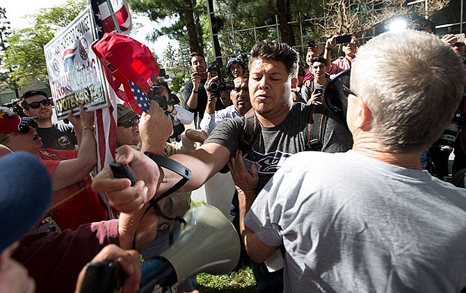 A man, center, sprays Republican presidential candidate Donald Trump supporters with pepper spray during a rally in front of the Anaheim City Hall on Tuesday, April 26, 2016, in Anaheim, Calif. (Leonard Ortiz/The Orange County Register via AP)