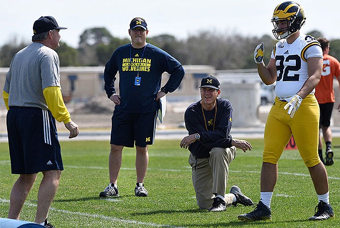 In this Feb. 29, 2016, file photo, Michigan's head coach Jim Harbaugh, center right, watches defensive coordinator Don Brown, left, work with Cheyenn Robertson during NCAA college football practice in Bradenton, Fla. The NCAAâ€™s Division I Board of Directors has rescinded the ban on satellite camps. The boardâ€™s action Thursday, April 28, 2016, comes almost three weeks after the Division I Council approved a proposal prohibiting Bowl Subdivision coaches from holding or working at camps and clinics away from their schools. (Tiffany Tompkins/The Bradenton Herald via AP, File)