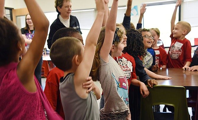 Students in Jaci Jacksonâ€™s first-grade class at Moreau Heights raise their hands to volunteer for an activity while visiting high school students in a Project Lead The Way class at Nichols Career Center in Jefferson City.