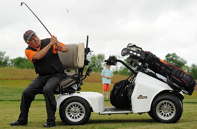 In this April 30, 2016 photo, Greenville College, Illinois, head golf coach Dany Baker takes a ceremonial tee shot on the first hole from the seat of his specialized golf cart during the grand opening celebration for the Ken Lanning Golf Center, the nation's first par 3 handicapped accessible golf course at Turkey Creek Golf Center in north Jefferson City.