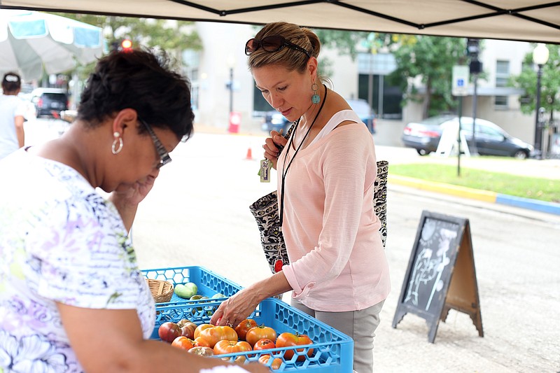 Maureen Willoh picks out heirloom tomatoes from Veronica Taylor's booth last year at the farmer's market in downtown Jefferson City.