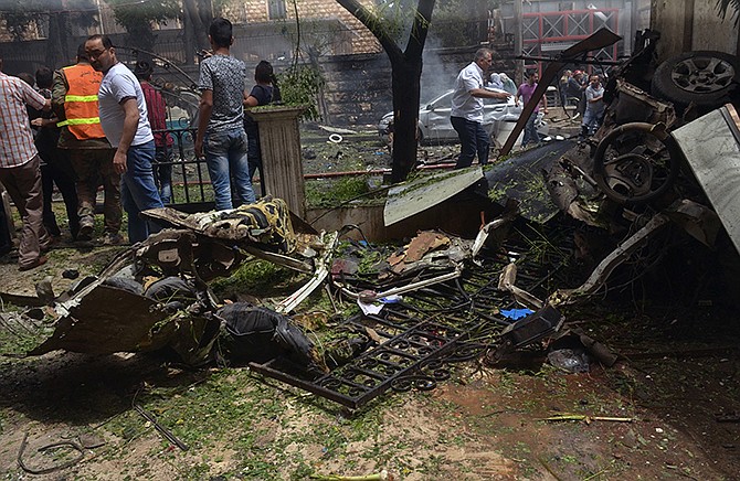 Syrian citizens and firefighters gather at the scene where one of rockets hit the Dubeet hospital Tuesday in the central neighborhood of Muhafaza in Aleppo, Syria.