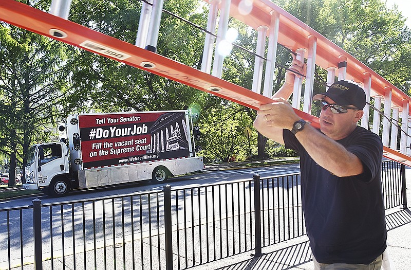Mark Boessen passes a rolling electronic billboard as he carries a ladder to the Missouri Supreme Court Building on Wednesday. Americans United for Change is using the billboard to pressure Sen. Roy Blunt and other Republican senators to hold a hearing on U.S. Supreme Court nominee Merrick Garland.
