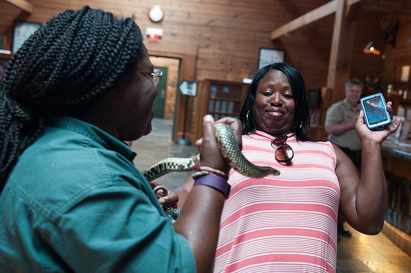 Teresa Ellis from Hope, Ark., leans away when given the opportunity to hold a speckled king snake, named King Louie, by Aneesah Rasheed from the Arkansas Game & Fish Commission during the National Travel and Tourism Days celebration Wednesday, May 4, 2016 at the Texarkana, Ark., Welcome Center.