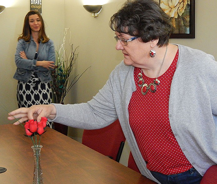 Brenda Rose, who retired from 2010 from Central Missouri Community Action in Fulton, examines carved wooden roses in a newly designed conference room named after her on Thursday.