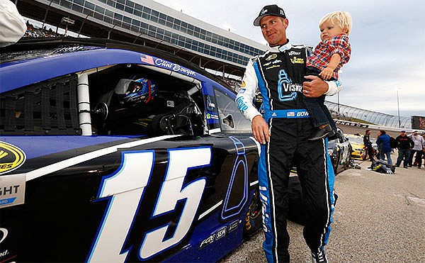 Clint Bowyer (15) carries his son Cash Bowyer before the start of the NASCAR Sprint Cup Series auto race at Texas Motor Speedway in Fort Worth, Texas, Saturday, April 9, 2016.