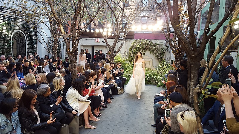 In this April 15, 2016 photo, a jumpsuit with tulle train from Monique Lhuillier's Spring 2017 bridal collection is modeled during Bridal Fashion Week in New York. The designer incorporated lingerie-inspired elements in other looks, with a touch of color in rose, pistachio, antique ivory and caramel.