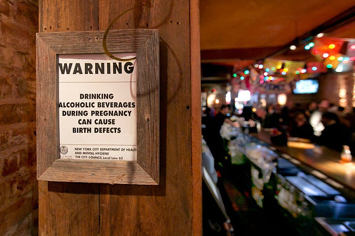 The drinking and pregnancy warning notice is posted behind the bar at the Mad Dog & Beans Mexican Cantina, in New York's Financial District, Friday, May 6, 2016. Pregnant women can't be barred from New York City bars or refused alcoholic drinks just because they're expecting, under new official guidance on a city rights law. Human Rights Commission officials say they're not saying that expectant mothers should drink, but that such health decisions are up to the woman, not a bartender.