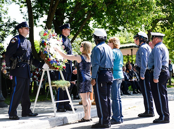 On Saturday, May 7, 2016, family members place carnations in the memorial wreath for their loved ones who were killed during their service as law enforcement officers during the Service Roll Call of Heroes outside the Missouri Capitol.