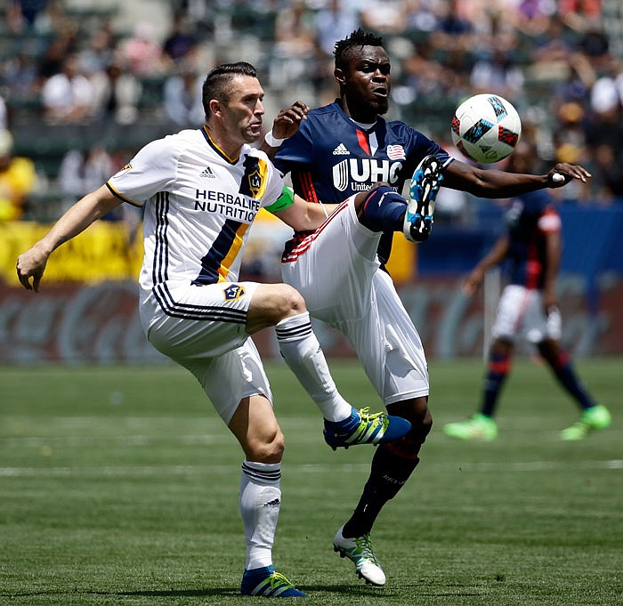 New England Revolution midfielder JeVaughn Watson, right, kicks the ball away from Los Angeles Galaxy forward Robbie Keane during the first half of an MLS soccer game on Sunday, May 8, 2016 in Carson, Calif.