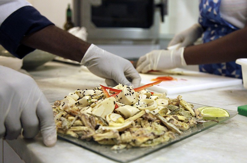 In this May 6, 2016 photo, cooks prepare meals during the food-testing of the Olympic menu in Rio de Janeiro, Brazil. Diners will choose from five different buffets: Brazilian, Asian, International, Pasta and Pizza, Halal and Kosher. 