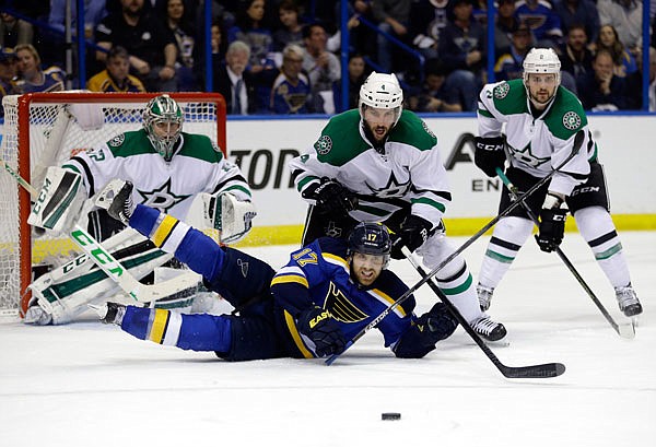 Jaden Schwartz of the Blues falls while reaching for a puck as (from left) Kari Lehtonen, Jason Demers and Kris Russell look on during Monday night's game in St. Louis.