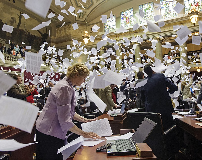 Rep. Deb Lavender, D-Kirkwood, gathers loose papers on her desk Friday before joining in with her fellow legislators as they toss their papers in the air following the adjournment of the second regular session of the 98th General Assembly.