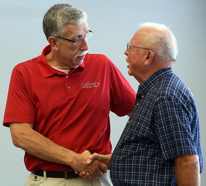 John Engelbrecht, left, shakes hands with Gerry Wolf, right, at a Engelbrecht's retirement party Saturday at Calvary Lutheran High School in Jefferson City.