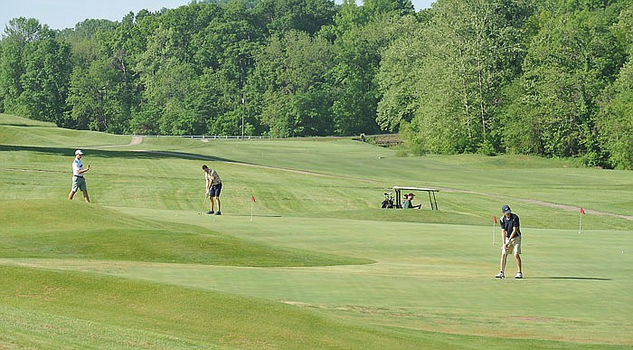 Former Helias High School classmates, Brock Gerstner, left, Matthew Rehagen and Christian Hake practice on the putting green while waiting to play Friday morning at Railwood Golf Course. While they were waiting for the rest of their group, others teed off on the first hole, which has recently been reopened.