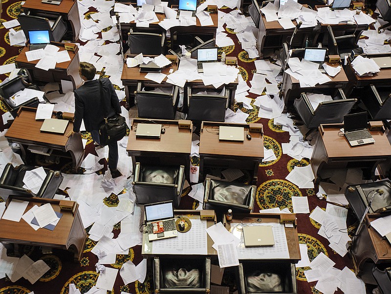 State Rep. Jay Barnes, R-Jefferson City, left, makes his way through the paper-covered House of Representatives floor after gathering his things from his desk following the adjournment of the second regular session of the 98th General Assembly May 13.