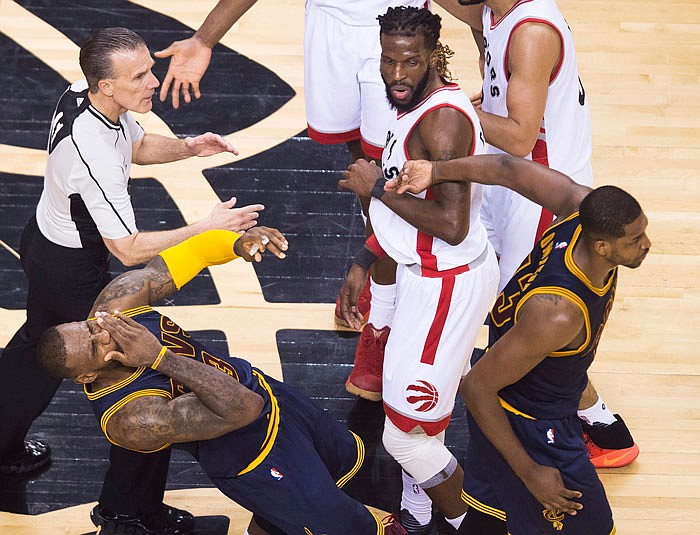 LeBron James of the Cavaliers (left) falls back after being struck by teammate Tristan Thompson (right) as DeMarre Carroll of the Raptors looks on during the first half of Saturday night's game in Toronto.