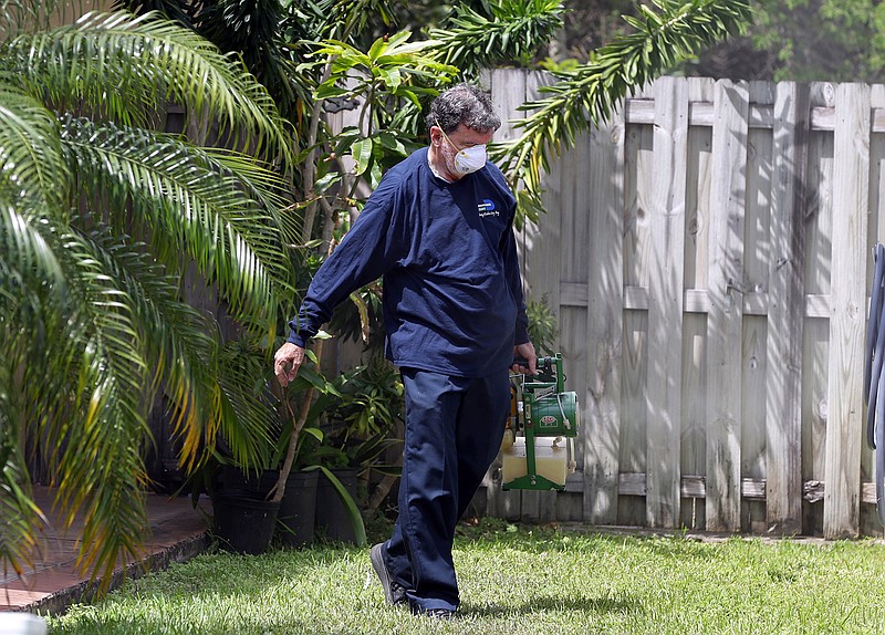 In this photo taken April 12, 2016, Giraldo Carratala, an inspector with the Miami- Dade County, Fla. mosquito control unit, sprays pesticide in the yard of a home in Miami, Fla. Beg, borrow and steal: Zika preparation involves a bit of all three as federal, state and local health officials try to get a jump on the mosquito-borne virus while Congress haggles over how much money they really need. With the money in limbo, it's all about shifting resources.