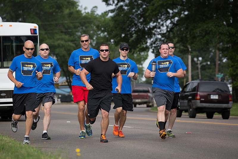 Members of the Texarkana, Ark., Police Department head down Arkansas Boulevard on Tuesday morning, May 24, 2016, to kick off the 2016 Special Olympics Torch Run. TAPD has participated in the run for nearly 20 years. The group runs the torch 18 miles to the Miller/Hempstead county line, where it is handed off to the Hope Police Department.