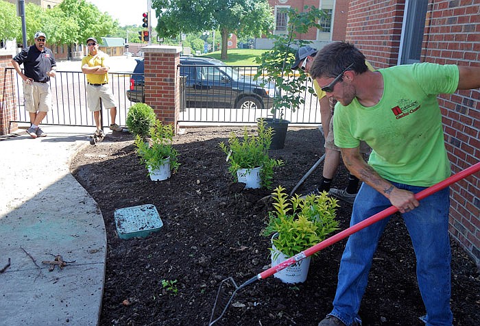 Landscapers creating a garden at the corner of Market and Fifth streets strive to complete the project before weekend storms arrive.