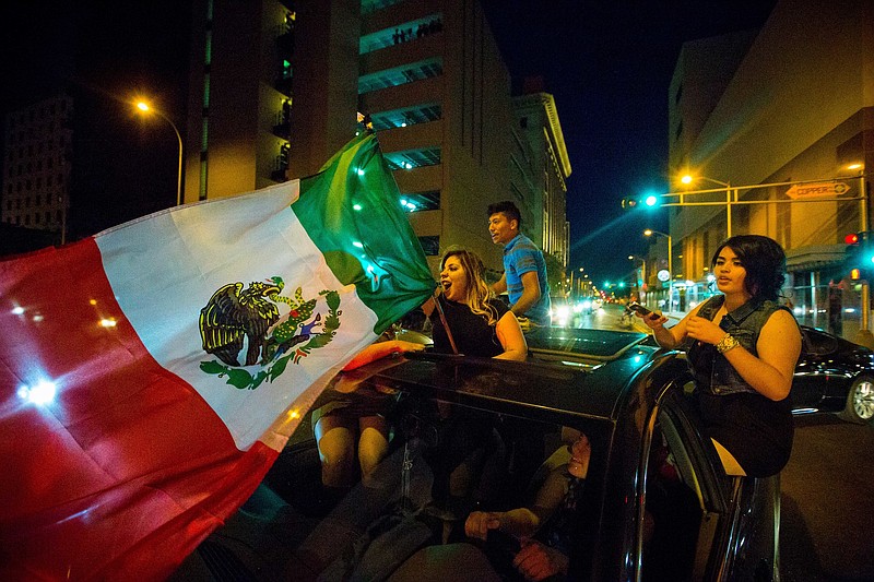 In this May 24, 2016, photo, a woman waves the Mexican flag while driving past the Albuquerque Convention Center after a rally by Republican presidential candidate Donald Trump in Albuquerque, N.M. Hispanic voters in Florida, New Mexico and California have waved Mexican flags and bashed Donald Trump pinatas to protest the Republican presidential contender's hard line approach to immigration. Yet far from the protests, an increasingly vocal Hispanic minority is speaking out in favor of the brash billionaire.
