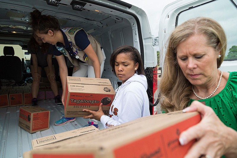 Shaleigh Chandler, Malena Haflich and Mariah Jones of Girl Scout Troop 2413 load cookies onto carts with the help of Dawn Prasifka, Girl Scouts Diamonds of Arkansas, Oklahoma and Texas president and CEO, Thursday,  at Watersprings Ranch. The Girl Scouts have donated 12,000 boxes of cookies across Arkansas and 65 cases of cookies to Watersprings Ranch. Texarkana, Ark., is the only place to receive donated Samoas in Arkansas.