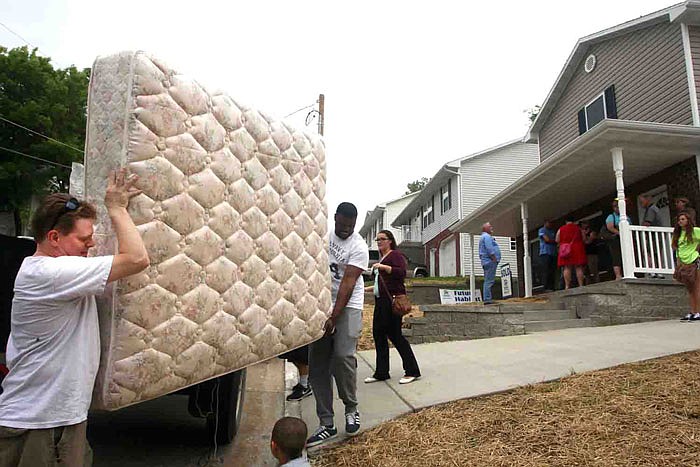 Erik Bonta, left, carries his mattress into his newly constructed house built by River City Habitat for Humanity.
