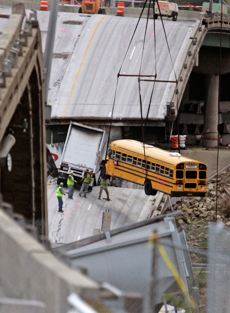 In this Aug. 12, 2007 file photo, workers remove a school bus from the interstate 35W bridge collapse site in Minneapolis. The school bus was carrying 52 children from a visit to a water park when it dropped with the bridge during the collapse. All the children survived the fall. According to court testimony in a federal terrorism trial, Mohamed Roble, who was one of the passengers on the bus, is now believed to be in Syria with the Islamic State group. 