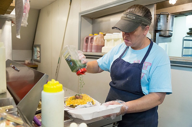 Stacey Smith pours chives on a Ranch Special potato Thursday, May 26, 2016 at The Potato Patch. The Ranch Special is one of the most popular options at the restaurant.