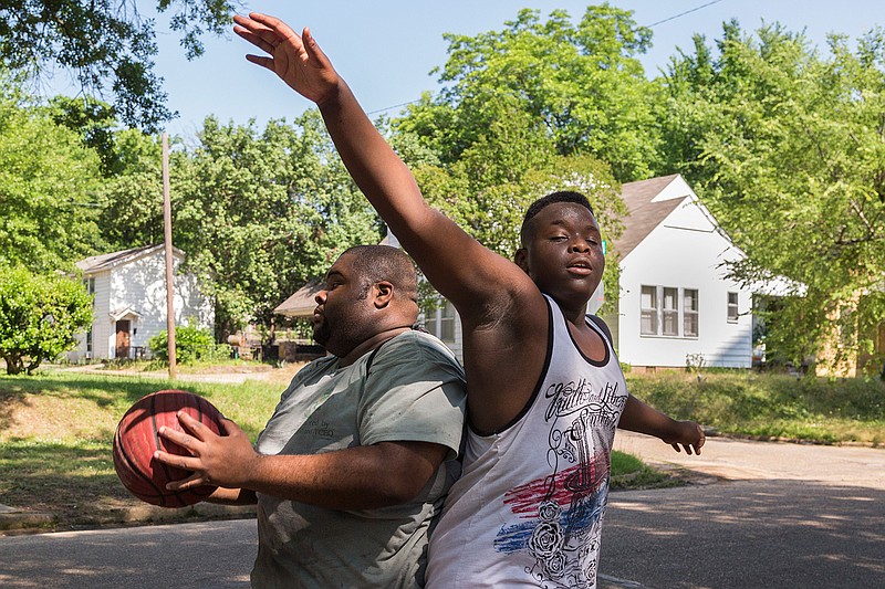 Decoya Walker, left, recovers the ball as Tyrane McBride, 14, returns to the ground after jumping trying to do the same during a casual basketball game on Saturday, May 28, 2016 in Texarkana, Texas. The two were joined by six neighbors of all ages who play pickup games regularly. Each time they play, they try to make each team a good mix of ages and skill levels. "The best thing about playing is the people you play with," Walker said. 