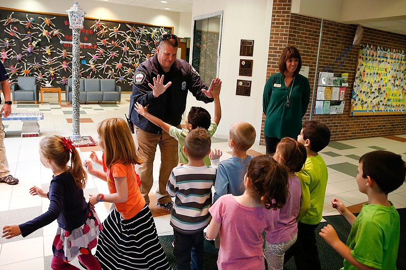 In this May 6, 2016, photo, Forest Dale Elementary School principal Deanna Pitman, right, and Carmel, (Ind.) police officer Greg DeWald welcome students as they return to the school following an intruder drill at the school in Carmel, Ind. More and more, schools these days are conducting active-shooter drills. A government report found that more than two-thirds of the school districts surveyed conduct active shooter exercises. 
