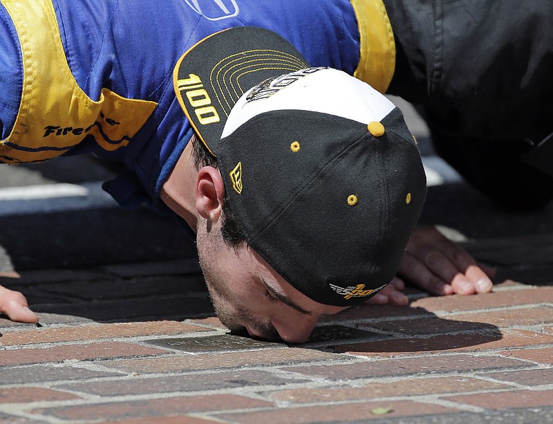 Alexander Rossi kisses the bricks on the start/finish line after wining the 100th running of the Indianapolis 500 auto race at Indianapolis Motor Speedway in Indianapolis, Sunday, May 29, 2016. 