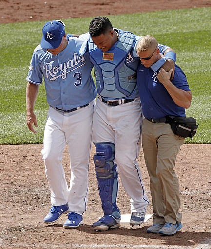 Kansas City Royals catcher Salvador Perez, center, is helped off the field after getting injured catching a fly foul ball for the out on Chicago White Sox's Adam Eaton during the ninth inning of a baseball game Saturday, May 28, 2016, in Kansas City, Mo. Third baseman Cheslor Cuthbert slid into Perez just after the catch.