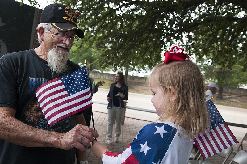 Marine Corps veteran Dwight Nevill takes a flag from Allee Carter  on Monday after the Memorial Day service at the Korea-Vietnam Memorial in downtown Texarkana.

 