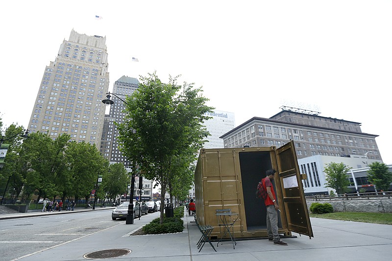 Timothy  Little  reads  over  information  about  a  container  outfitted  with  video  conference electronics that is part of an art installation on Friday at Military Park in downtown Newark, N.J.