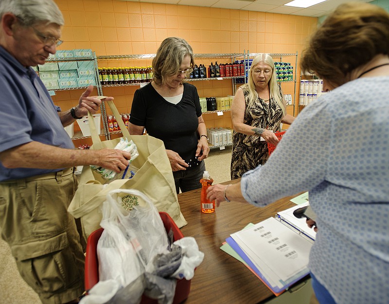 Bob Schmidt, left, and Connie Guthmiller, second from right, help a customer check out with Nancy Samp, right, as she uses her points Tuesday to purchase household goods and cleaning supplies from the Fresh Start Market at First United Methodist Church. Schmidt and Samp are both church members and volunteers, while Guthmiller volunteers to earn points to use in the market as a client.