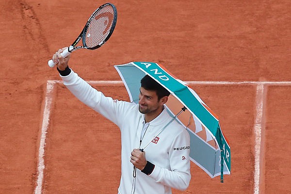 Novak Djokovic walks onto center court Tuesday with an umbrella he borrowed from a spectator before resuming his fourth round match against Roberto Bautista at the French Open in Paris.