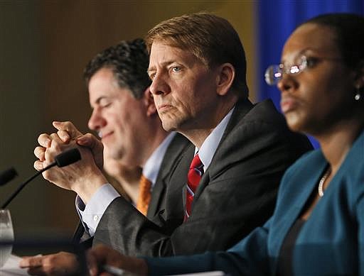 In this Thursday, March 26, 2015, file photo, Consumer Financial Protection Bureau Director Richard Cordray, center, listens to comments during a panel discussion in Richmond, Va. The CFPB announced Thursday, June 2, 2016, they are proposing a significant clampdown on payday lenders and other providers of high-interest loans, saying borrowers need to be protected from practices that wind up turning into "debt traps" for many. 