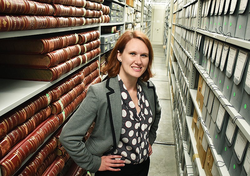 Mary Stansfield poses in the archives at the Missouri State Archives in the State Information Center in Jefferson City. The oversized red leather books are just a few of the tens of thousands of items stored in the climate controlled area of the archives.