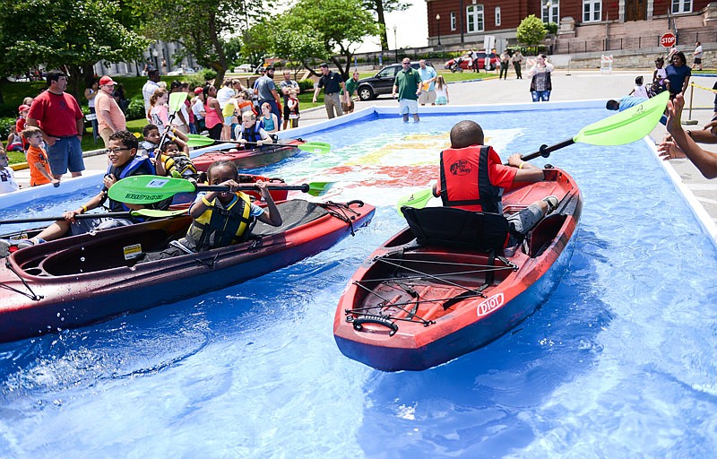 Parents watch as their children take turns crowding a small simulation pool Saturday where they can try their hand at kayaking and take a break from the heat during Outdoor Day at the Missouri Capitol.