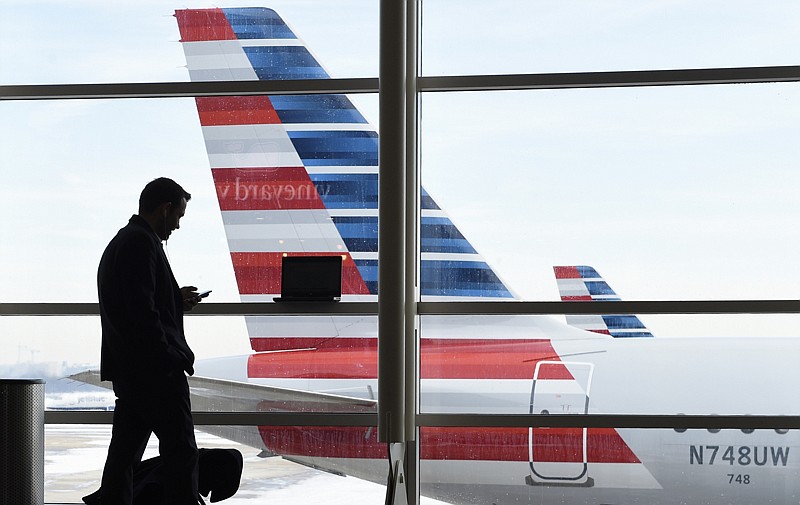 A passenger talks on the phone as American Airlines jets sit parked at their gates Jan. 25 at Ronald Reagan National Airport in Washington, D.C.